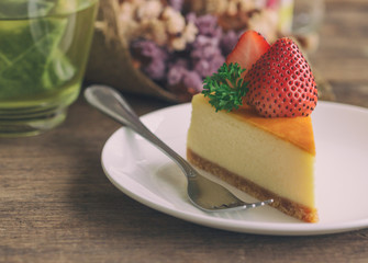 Homemade New York cheesecake on white plate decorated by strawberry and parsley. Moist and smooth classic style baked cheesecake. Copy space background of delicious strawberry New York cheesecake.