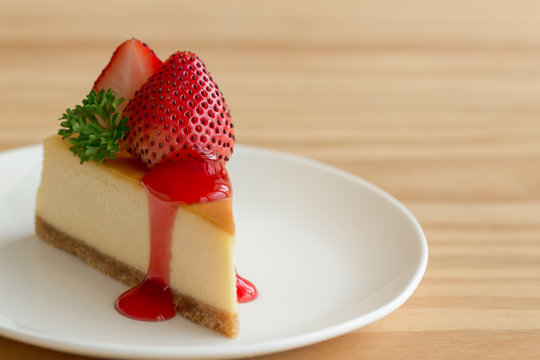 Homemade New York cheesecake on white plate decorated by strawberry,parsley and strawberry sauce. Moist and smooth classic baked cheesecake. Copy space background of delicious New York cheesecake.