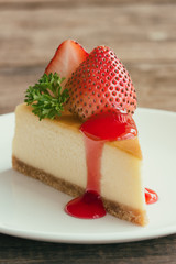 Homemade New York cheesecake on white plate decorated by strawberry,parsley and strawberry sauce. Moist and smooth classic baked cheesecake. Copy space background of delicious New York cheesecake.