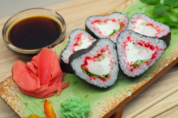 Роллы в форме сердца с имбирем и васаби на зеленой тарелке