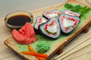 Роллы в форме сердца с имбирем и васаби на зеленой тарелке