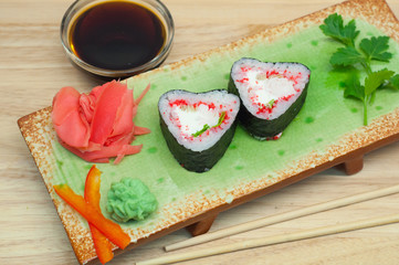 Роллы в форме сердца с имбирем и васаби на зеленой тарелке