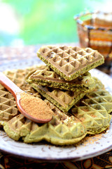 Homemade waffles with addition of matcha, pistachios, flax seeds. Decorated with coconut sugar.