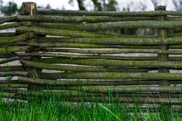 Vintage texture of an old wicker fence on green grass. Traditional rural decorative fence.