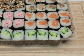 Японская еда роллы с имбирем и васаби в одноразовом контейнере на деревянном фоне