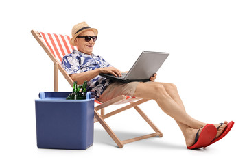 Tourist with laptop in deck chair next to cooling box
