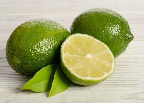 Juicy lime with its leaves on wooden background