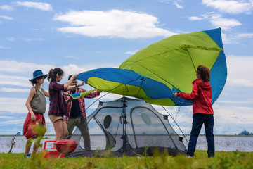 camping, travel, tourism, hike and people prepare and setting up tent outdoors in the park at lake