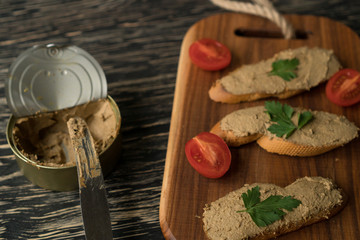 Liver pate on the bread on wooden tray.