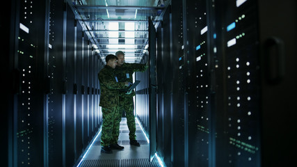 In Data Center Two Military Men Work with Open Server Rack Cabinet. One Holds Military Edition...