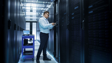 IT Engineer Installing Hard Drives into Working Rack Server. He's Working in Data Center.