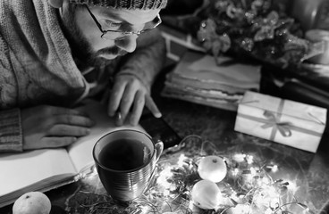 monochrome photo of man with a blank book in his hands for the New Year's table with decorations