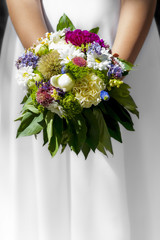 Woman/girl in white dress holding flowers at wedding/first holy communion.