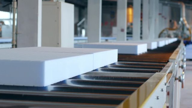 processing of styrofoam in factory, automated complexes manufacturing polyvinyl chloride foams, styrofoam on conveyor line, production equipment at plant, production of foam plastic,