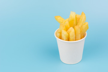 french fries in a paper cup on blue background