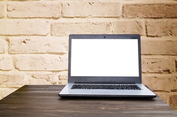 Laptop computer with white blank screen on wooden table with brick wall background, selective focus, copy space, sunlight effect, business working, online social media and searching data concept