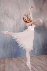 Fototapeta premium Beautiful legs of young ballerina dancing at white wooden floor background, with copy space. Ballet practice. Beautiful slim graceful ballet dancer. Spring and romantic atmosphere