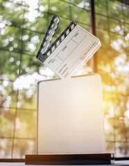 Movie clapper on glass trophies for winner award, blur light near window background, business...