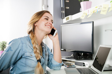 Woman working at home office while talking on phone