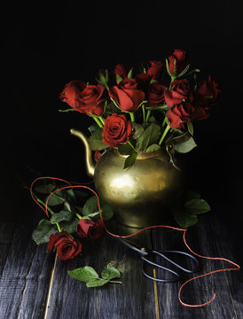 Bouquet of red roses in a copper jar with scissors selective focus, concept