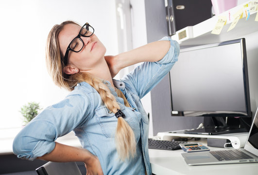 Woman in home office suffering from neck pain sitting at desk