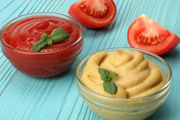 mustard ketchup in glass bowl on blue wooden background.
