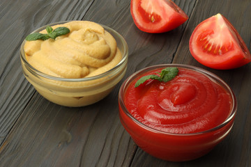 mustard ketchup in glass bowl on dark wooden background.