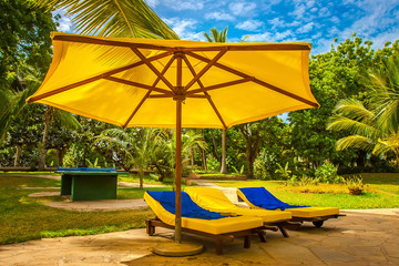 Sunbeds under a yellow umbrella. Relax on the beach. Relax by the pool.