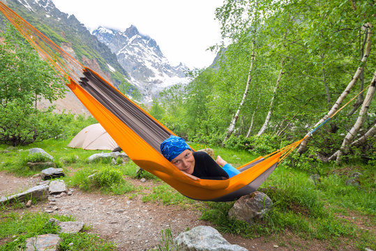 Happy funny woman traveler relaxing in hammock in the mountains
