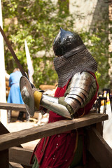 Middle ages period costume at knight tournament. Medieval historical reenactment - a man wearing metal helmet and armor suit, holding a sword and a shield