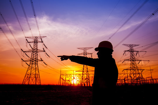 Electricity workers and pylon silhouette