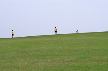 Fototapeta premium 広大な芝生の公園を歩く人たち