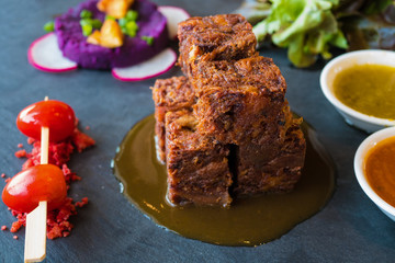 Close up  deep fried crispy pork knuckle cube with spicy sauce and tomato , Thai French fusion style