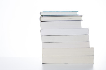 Pile of books isolated on white table. Closeup.