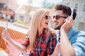 Break after shopping. Young couple listening to music with mobile phone and headphones. Dating, love and tenderness, lifestyle concept