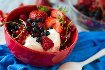 Healthy breakfast: cottage cheese with sour cream, strawberry, raspberry, blueberry, cherry and red currant on blue wooden table. Selective focus