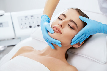 Doctor massaging face of beautiful woman