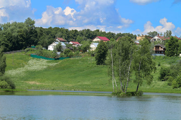 Panorama of a modern village with a lake and a green slope