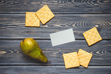 A healthy breakfast with biscuits and pear on old wooden table. Mockup of business card. Flat lay. Top view.