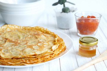 Thin russin pancakes on a plate on white wooden table. Healthy breakfast concept. close up.