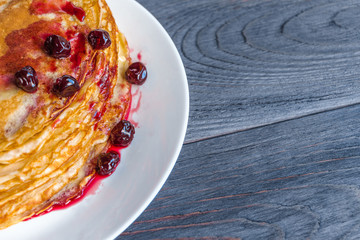 Thin russin pancakes with syrup on a plate on dark gray wooden table. Healthy breakfast concept. Close up. Flat lay. Top view with copy space.