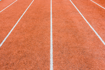 Close-up view of a red athletics track with white lines delimiting the lanes.
