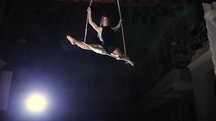 Female circus performer on a trapeze bar in slowmotion