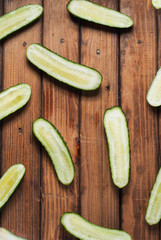Fresh cucumbers in slit on wooden background.