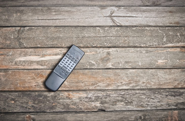 Vintage TV remote control on a wooden background. Top view.