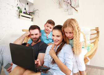 Happy family with two kids at home looking fun on laptop
