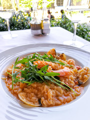 Tasty risotto with Shrimp, fresh herbs vegetables on a white plate