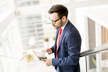 Young man with tablet on stairs in modern office