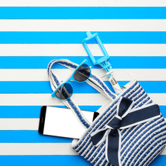 Beach accessories and smartphone on white and blue background. Top view, flat lay.