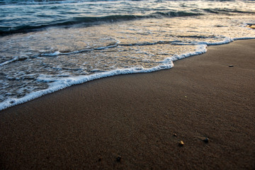 Waves approaching sandy beach during sunset